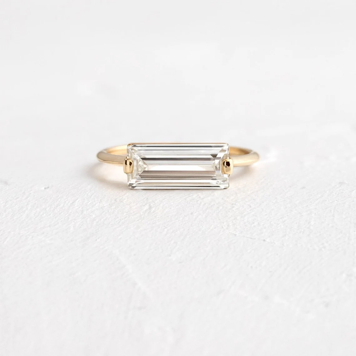 Streamlined silver setting holding a baguette moissanite with glassy clarity A piece that feels polished, structured, and effortlessly elevated Designed for contemporary elegance with a sharp edge