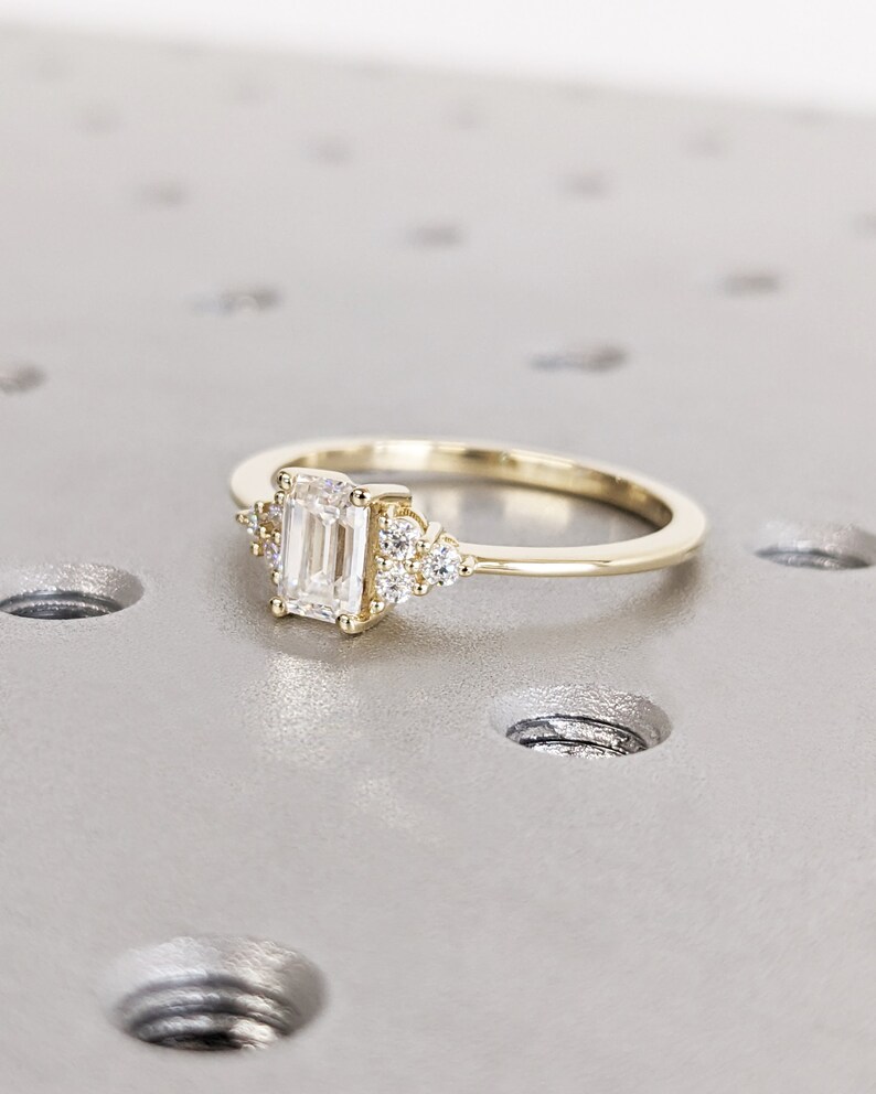 Delicate emerald-cut diamond engagement ring with side stones, set in 14K yellow gold, vintage-inspired minimalist design with elegant sparkle - Image 4