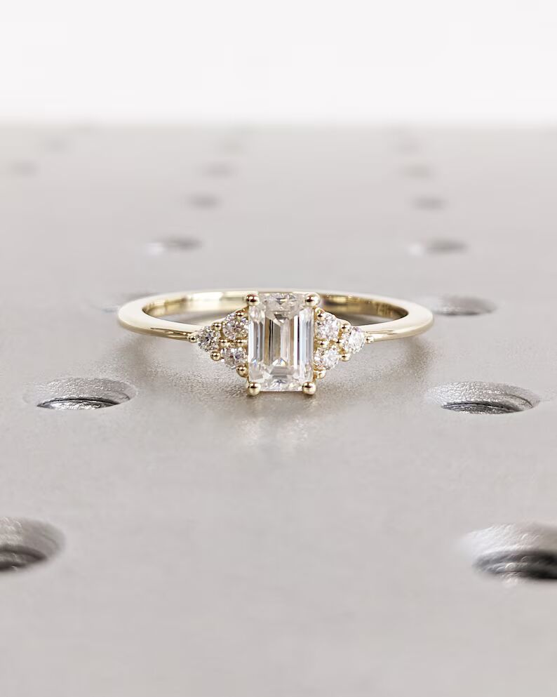 Delicate emerald-cut diamond engagement ring with side stones, set in 14K yellow gold, vintage-inspired minimalist design with elegant sparkle - Image 2