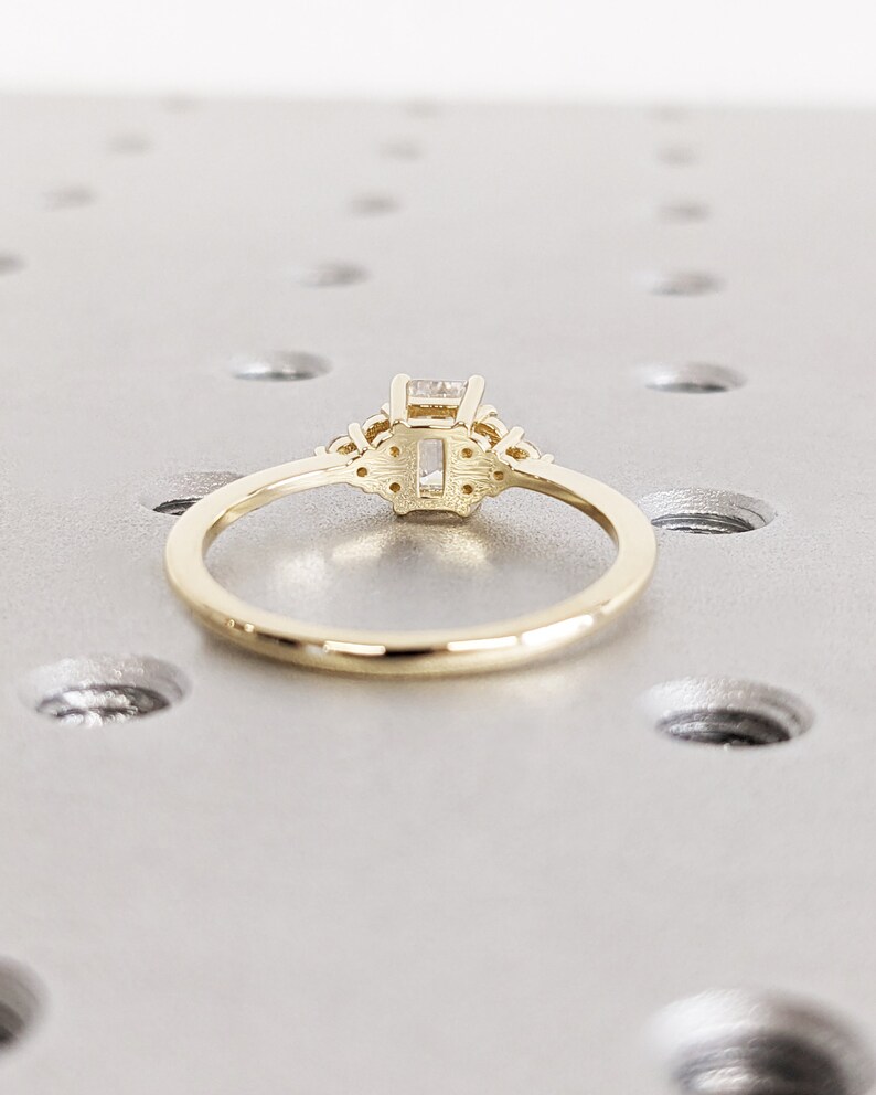 Delicate emerald-cut diamond engagement ring with side stones, set in 14K yellow gold, vintage-inspired minimalist design with elegant sparkle - Image 6