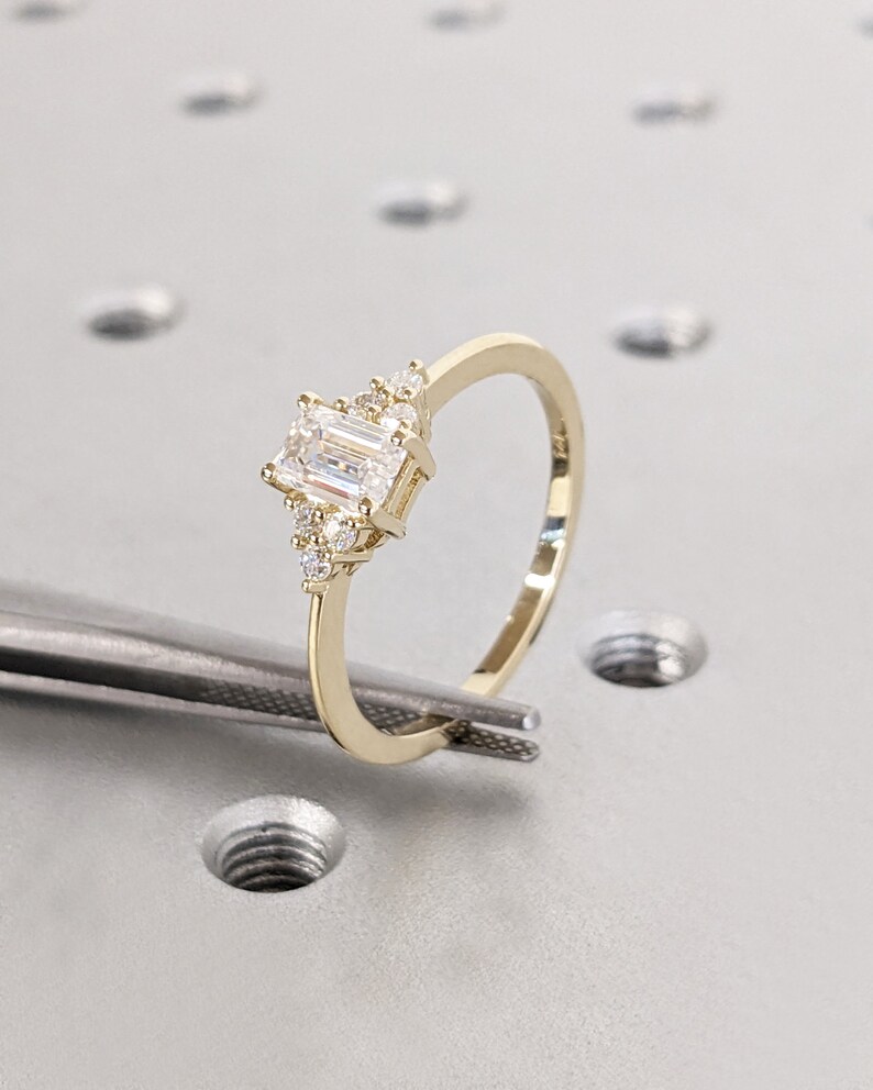 Delicate emerald-cut diamond engagement ring with side stones, set in 14K yellow gold, vintage-inspired minimalist design with elegant sparkle - Image 3
