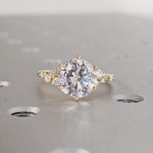 Suncrest Elegant round cut diamond engagement ring with sparkling side cluster accents, set in 14K yellow gold, vintage inspired design with delicate detail and radiant brilliance
