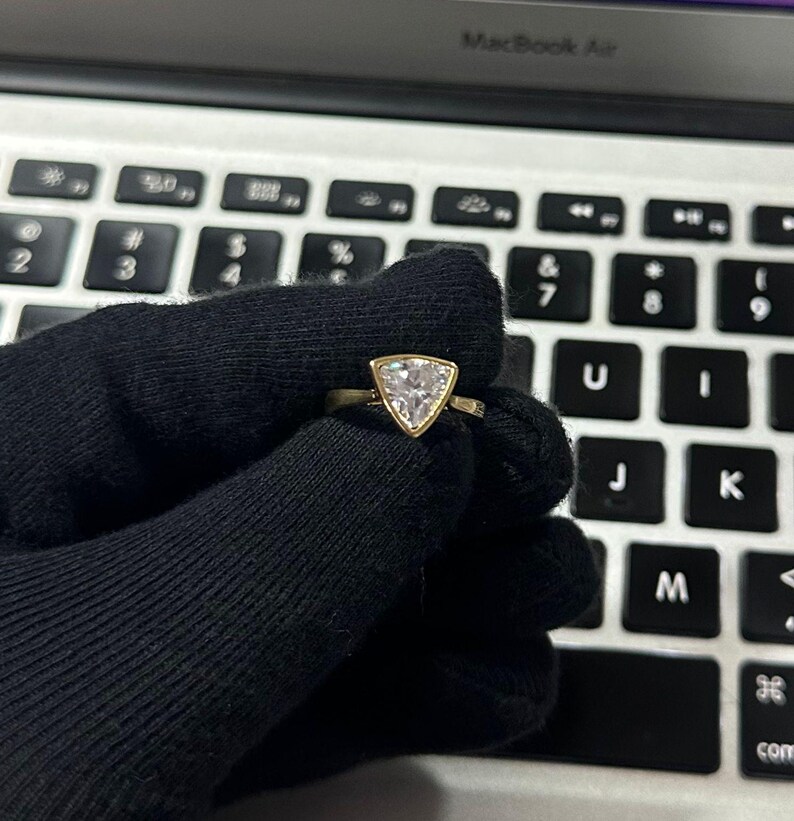 Trillion cut diamond solitaire engagement ring in a sleek bezel setting, crafted in 14K yellow gold Classic yet modern design with clean geometric lines, refined sparkle, and a bold sophisticated look