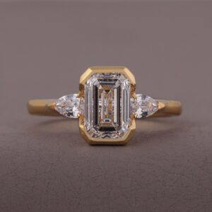 Eemerald cut diamond engagement ring with marquise side stones, crafted in 14K yellow gold Classic refined design with a sleek bezel setting, timeless beauty, and brilliant sparkle