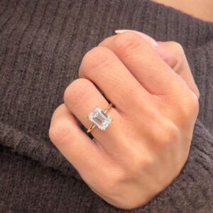 Infinite Charm solitaire engagement ring featuring a stunning elongated emerald-cut diamond with crisp clean step facets, set in a sleek polished 14K yellow gold band, showcasing timeless sophistication, modern luxury, and refined brilliance with a bold yet graceful presence