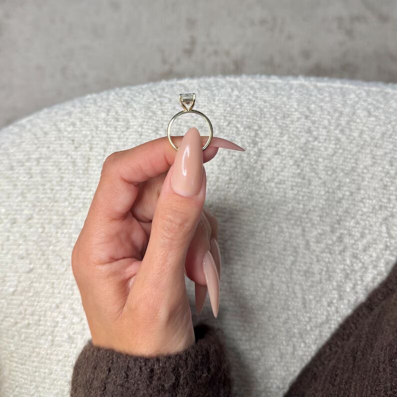 Infinite Charm solitaire engagement ring featuring a stunning elongated emerald-cut diamond with crisp clean step facets, set in a sleek polished 14K yellow gold band, showcasing timeless sophistication, modern luxury, and refined brilliance with a bold yet graceful presence - Image 2