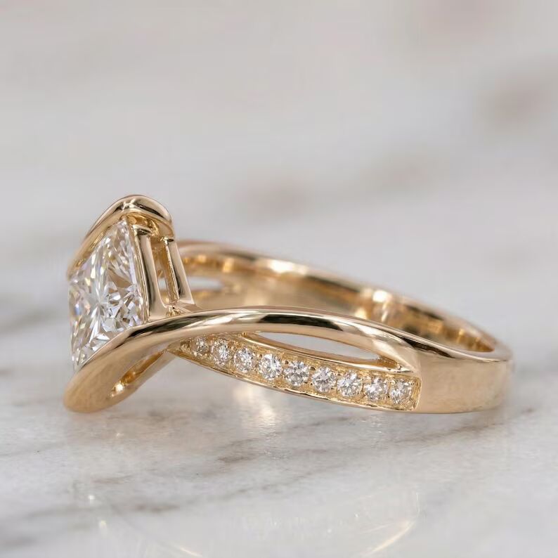 Unique modern engagement ring featuring a dazzling princess cut diamond centerpiece set on a graceful twisted crossover design, accented with sparkling pavé stones along a sleek 14K yellow gold band, offering a bold contemporary style with elegant curves, radiant brilliance, and eye catching sophistication - Image 3
