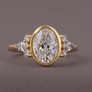 Fancy oval cut diamond engagement ring with cluster side stones, crafted in 14K yellow gold Classic bezel set design with timeless beauty, soft curves, and radiant luxurious sparkle